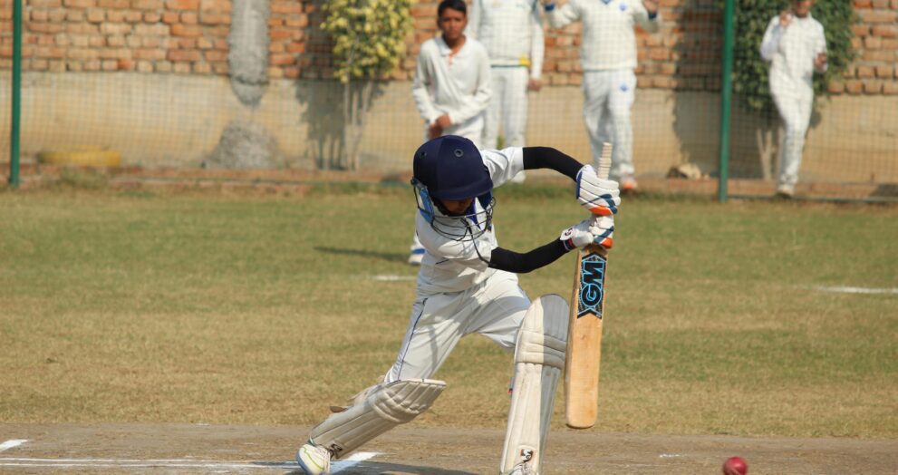 A young cricket player bats during a game on a sunny day in Gurugram, India.