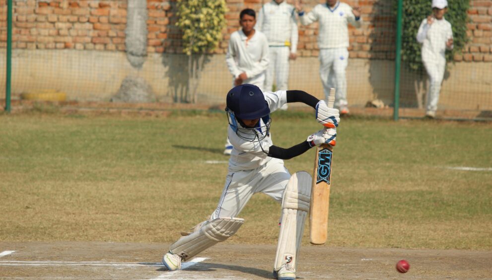 A young cricket player bats during a game on a sunny day in Gurugram, India.